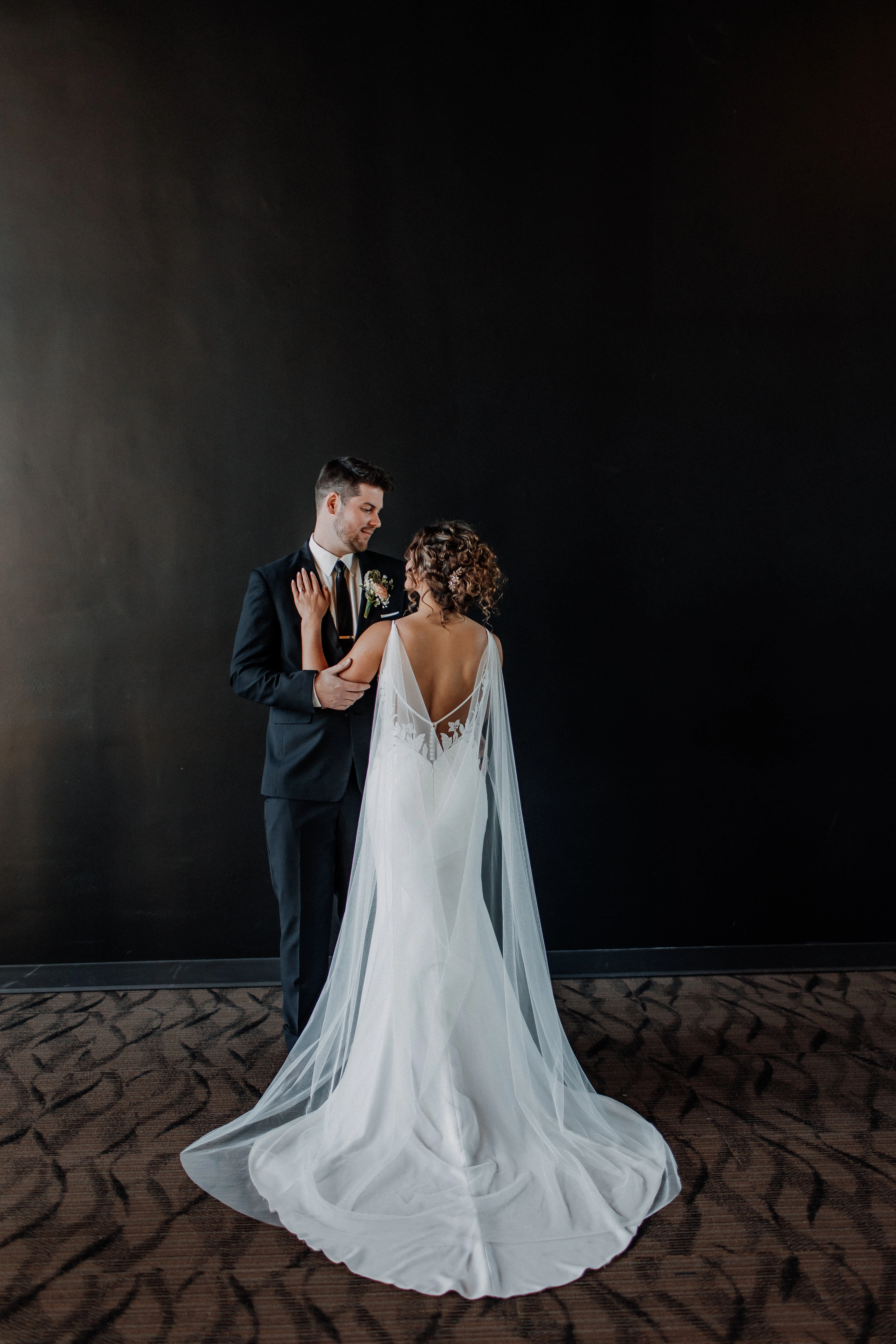 Bride wearing Kern backless wedding dress by Maggie Sottero embracing her husband.